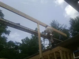 Carpenter setting a ridge beam over a new addition frame — Ice Dam Removal by Roofing Brothers in Conrad