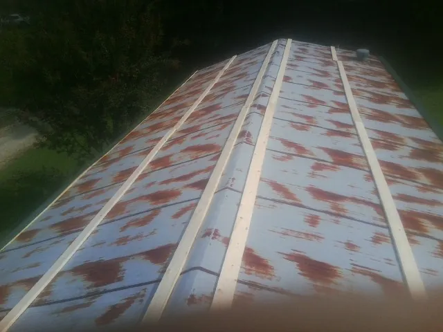 Rusted metal roof panels with new wood purlins before replacement — Storm Damage Roof Repair in Conrad by Roofing Brothers