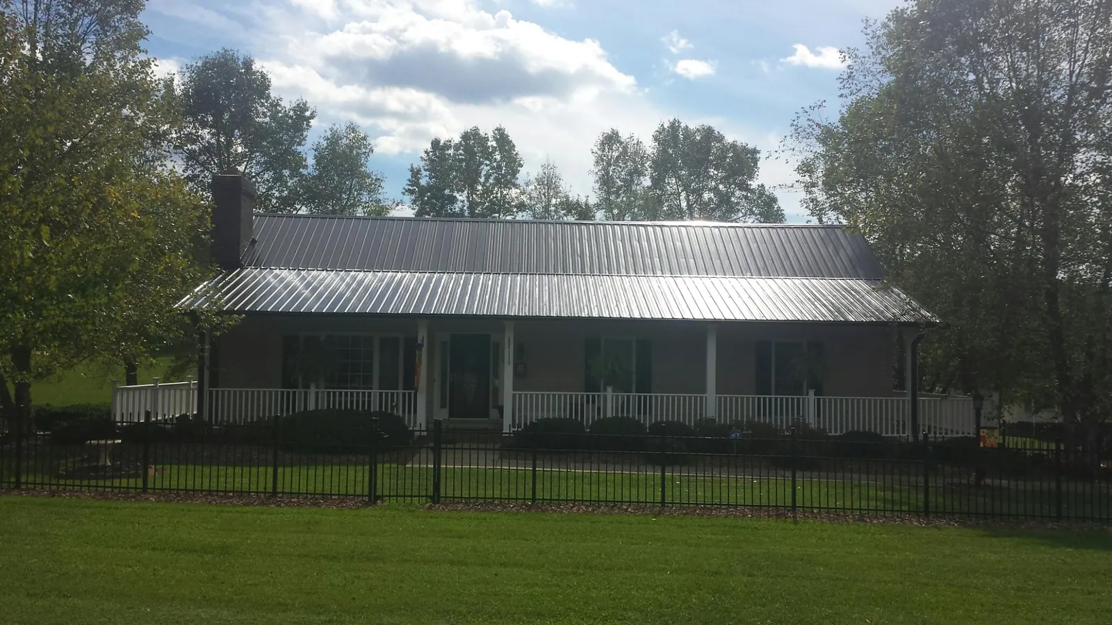 Gray metal roof on a brick ranch with a full width front porch — Gutter Guard Installation work by our crew in Conrad