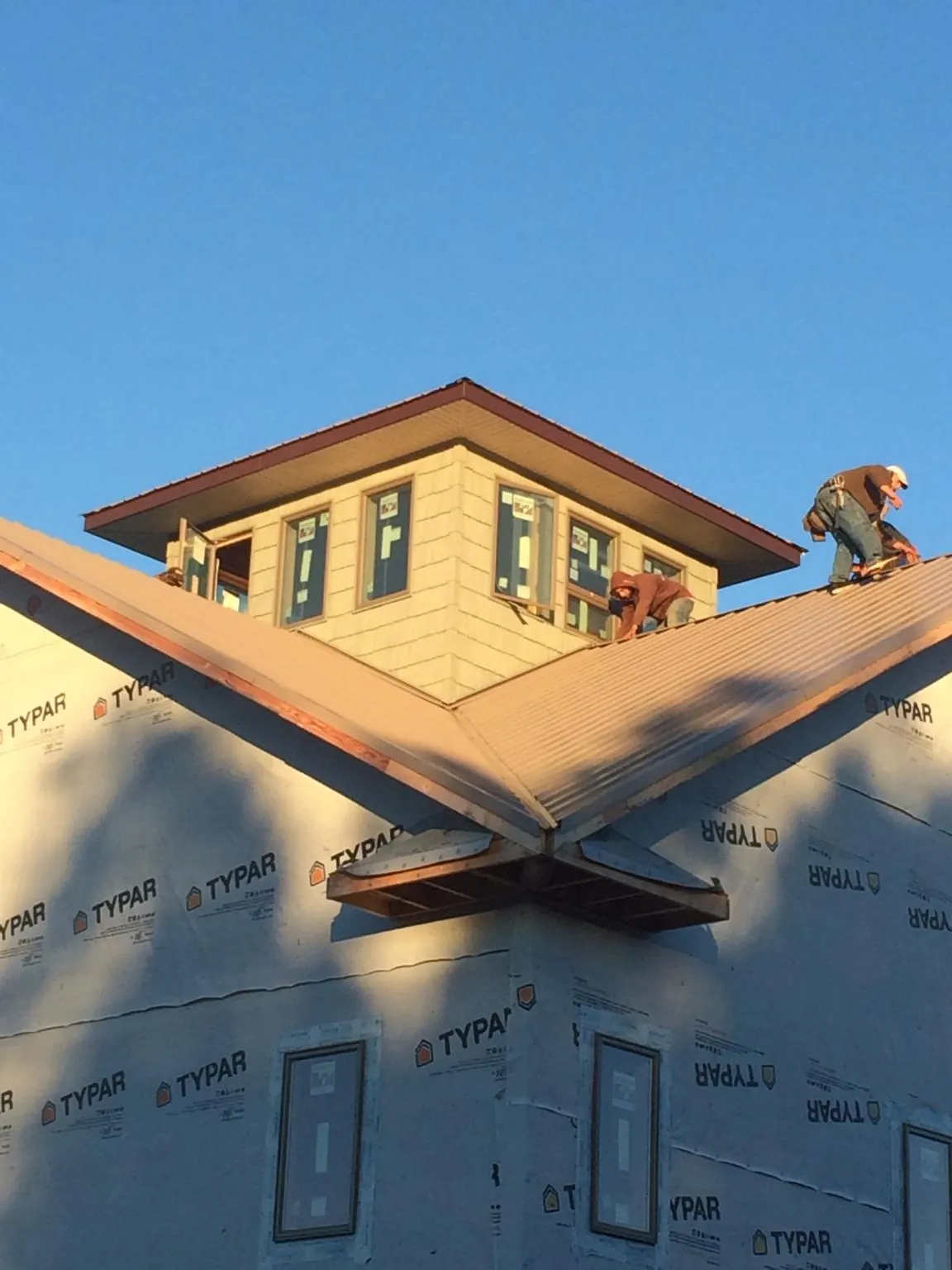 Roofers working around a rooftop cupola on a new metal roof at sunset — Roof Waterproofing in Conrad by Roofing Brothers
